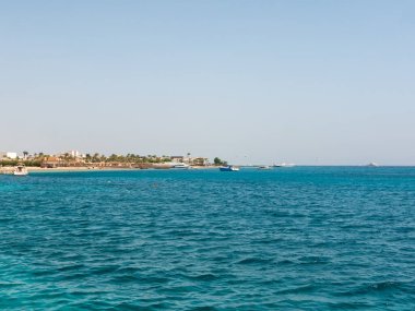 Hurghada, Mısır - 22 Eylül 2021: Kızıl Deniz 'in masmavi suyu ve kumlu Mısır plajının manzarası. Tekneler ve yatlar kıyıya yakın duruyor. Boşluğu kopyala.