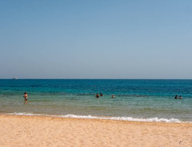 Hurghada, Mısır - 22 Eylül 2021: İnsanlar mavi gökyüzüne karşı kızıl denizin masmavi sularında yüzer ve şnorkelle yüzerler. Boşluğu kopyala.