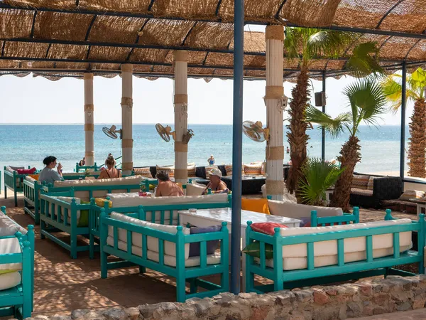 Hurghada, Mısır - 22 Eylül 2021: Kızıl Deniz kıyısındaki sahil barı. İnsanlar masalarda yastıklarla kanepelerde oturup konuşuyorlar..
