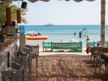 Hurghada, Mısır - 22 Eylül 2021: Kızıl Deniz sahilindeki barın görüntüsü. Uzun, gri, tahta sandalyeler barın yanında..