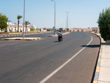 Safaga, Mısır - 27 Eylül 2021: Mesafeye giden ana yolun görüntüsü. İnsanlar yakınlardaki bir kasabaya motosikletle gidiyorlar..