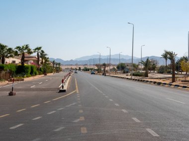 Safaga, Mısır - 27 Eylül 2021: Dağların ve mavi gökyüzünün arkaplanına uzanan ana yolun görüntüsü. Arabalar otoyol boyunca komşu bir şehre gidiyor..