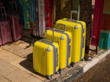 Cairo, Egypt - September 30, 2021: Cairo street with local tourist shops. Bright oriental-style scarves and yellow suitcases are sold outside the store. Close-up. clipart