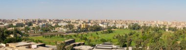 Giza, Kahire, Mısır - 30 Eylül 2021 Kahire 'nin panoramik manzarası. Şehir binalarının arka planında uzun palmiyeler olan yeşil park.
