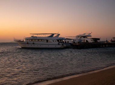 Hurghada, Mısır - 3 Ekim 2021: Mısır 'da Kızıldeniz' de güzel bir gün doğumu. Yatlar kumsaldaki rıhtımın yanında..