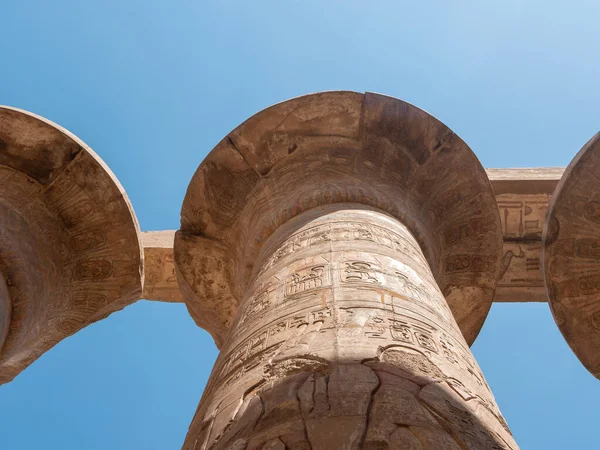 Mısır hiyeroglifleri ve Karnak Tapınağı 'ndaki antik çizimlerin bulunduğu taş sütun mavi bir gökyüzünün arka planına karşı. Yakın plan. Luxor, Mısır.