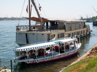 Luxor, Mısır - 3 Ekim 2021: Nil Nehri manzarası ve Luxor kıyıları. İnsanlar teknede oturup kıyıya çıkmak için davetiye bekliyor..