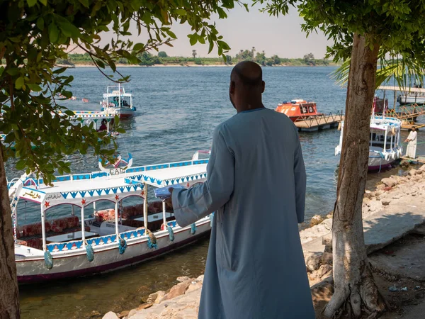 エジプトのルクソール 2021年10月3日 ナイル川とルクソールの海岸線の眺め エジプトの民族衣装はナイル川の岸に立ってボートを見る — ストック写真
