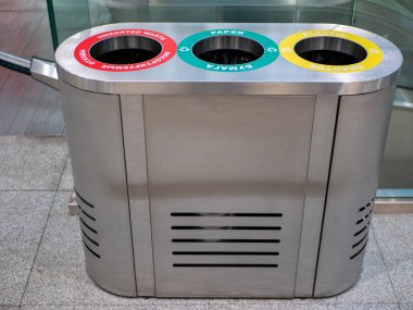 Demir bir çöp tenekesine yakın çekim. Çöpü plastik, kağıt ve sıralanmamış atıklara ayırmak farklı renklerle işaretlenmiştir. Temizlik kavramı.