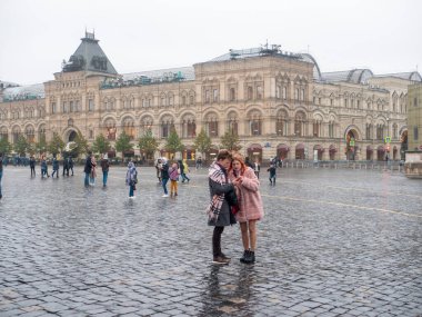 People walk and take pictures on Red Square on an autumn day. The girl in the Russian national headdress kokoshnik. Russia. Moscow. 05.10.2021.