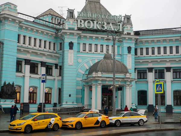 Moskova, Rusya - 5 Ekim 2021 Belorussky tren istasyonu, ana giriş. İnsanlar binanın girişinde dikiliyorlar. Taksi arabaları yol kenarında sıra sıra bekliyor..