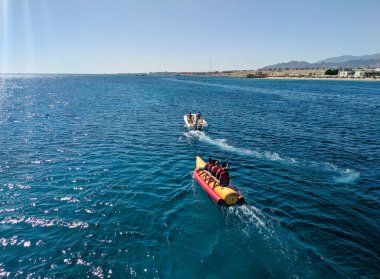 Hurghada, Mısır - 1 Ekim 2021: İnsanlar suyun üzerinde oturur muz teknesine biner ve Kızıl Deniz 'e biner.