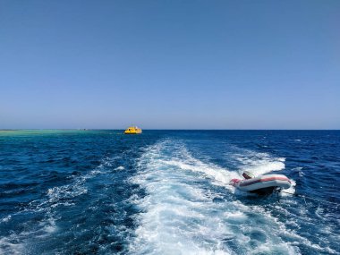 Hurghada, Mısır - 1 Ekim 2021: Mavi gökyüzüne karşı Kızıldeniz 'in güzel manzarası. Lastik bot yata bağlandı ve onu takip ediyor. Boşluğu kopyala.