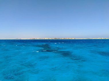 Mısırlı otellerin ve mavi gökyüzünün arka planında mercan resifi olan Kızıldeniz 'in güzel manzarası. Hurghada, Mısır. Boşluğu kopyala.