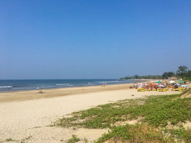 Kuzey Goa, Hindistan - 4 Aralık 2018: Morjim plajının güzel manzarası. İnsanlar dinlenip Hint Okyanusunda yüzüyorlar. Boşluğu kopyala.