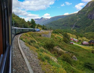 Flom, Norveç - 27 Ağustos 2017 Flam tren vagonundan yüksek dağlara ve mavi gökyüzüne karşı kırmızı ahşap evlere güzel bir manzara.