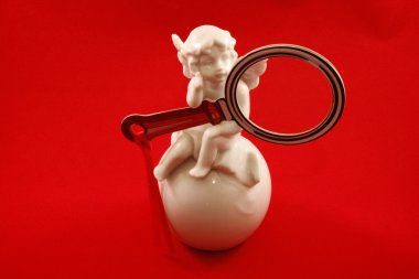 elinde kırmızı bir arka plan ile bir büyüteç ile bir küre üzerinde oturan melek