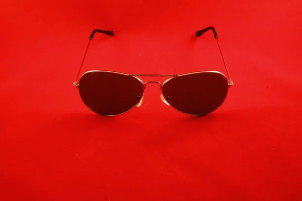 Fotograferade solglasögon med metallram på en röd bakgrund — Stockfoto