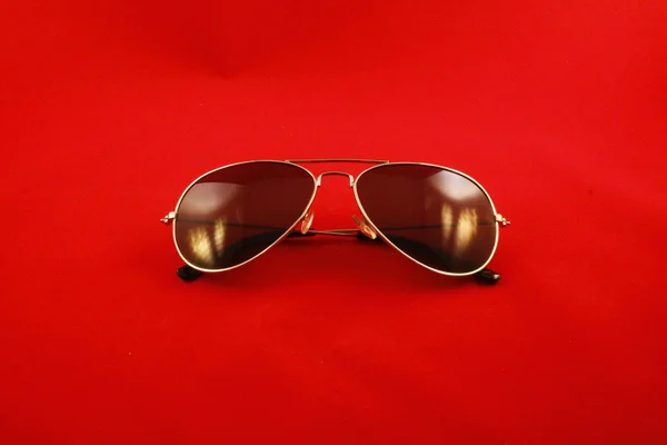 Gefaltete Sonnenbrille mit Lichtreflexion und rotem Hintergrund lizenzfreie Stockbilder