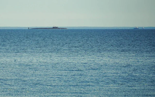 Russian military submarine on the horizon of the bay or sea. Summer blue water 免版税图库图片