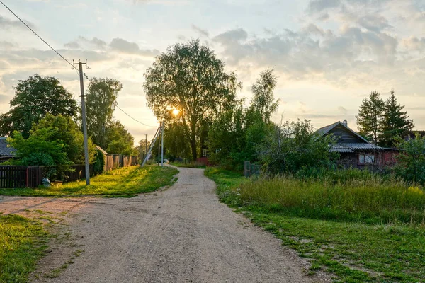 Pueblo ruso en Novgorod Oblast. Casa de madera y camino de grava. Puesta de sol de verano Fotos de stock libres de derechos