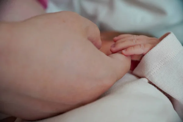 The hand of a mother and a newborn baby. The palm holds the finger close up view — Fotografia de Stock