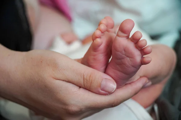 Legs with fingers are a newborn baby. Mother holds in the palm of her hand. — Stockfoto