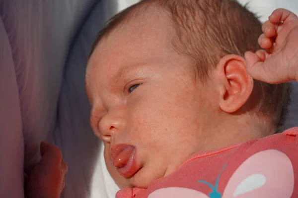 A newborn baby child show tongue. Close-up of the face. 图库照片