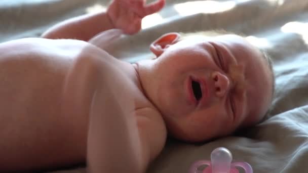 Gråtande nyfött barn på en säng med järnsilverskallra och napphållare — Stockvideo
