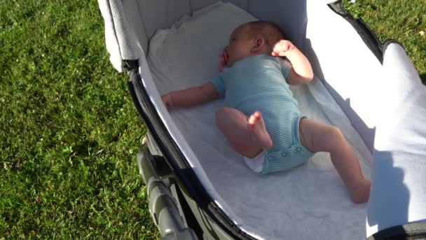 A baby caucasian child with a pacifier in his mouth relaxes lying on his back. — Vídeo de Stock