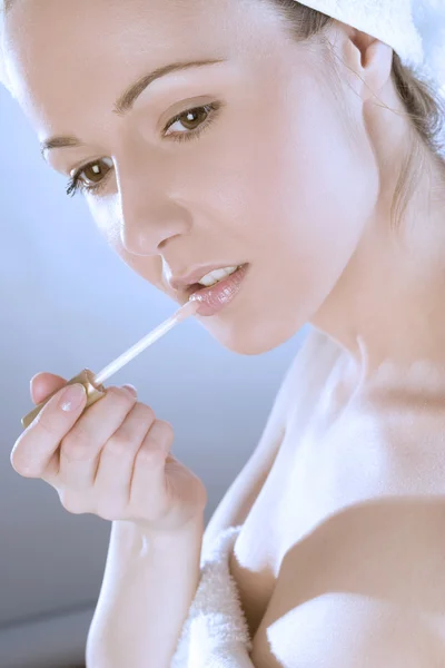 Jeune femme dans la salle de bain appliquant brillant à lèvres Photo De Stock