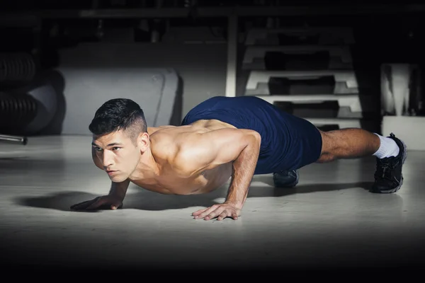 Muscular man doing push ups at gym — Stock Photo, Image