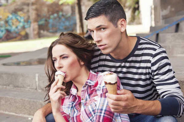 Молодая пара ест мороженое на открытом воздухе — стоковое фото