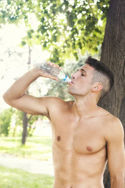Gespierde man drinkwater buiten na joggen — Stockfoto