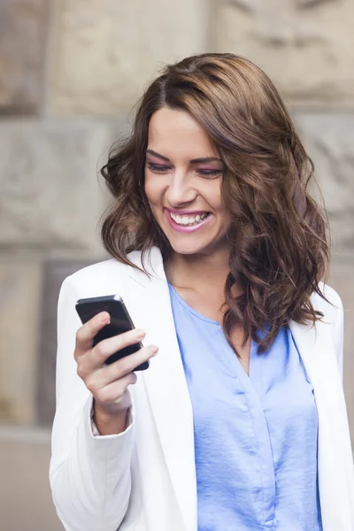 Mujer joven y feliz leyendo un mensaje de texto en su teléfono — Foto de Stock