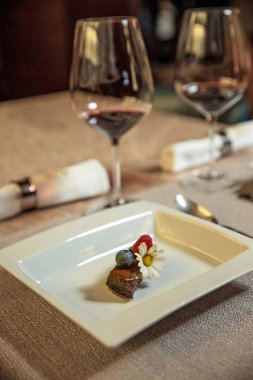 Meyve ve çiçekle süslenmiş çikolatalı pasta restoranda bir masada servis ediliyor.