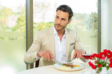 Çekici bir adam otel restoranında yemek yiyor.