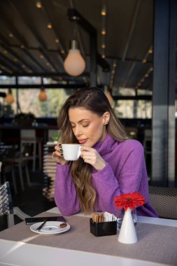 Güzel bir kadın kahve içiyor, eğleniyor, kapalı gözlerle, restoranda.