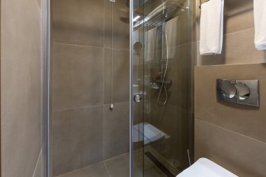 Cam duş kabini olan bir otel banyosu.