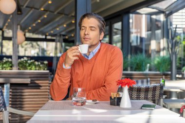 Kapalı gözlü yakışıklı adam, elinde sıcak sabah kahvesi tutuyor.