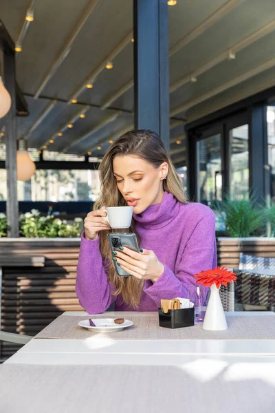 カフェバーでコーヒーを飲みながら携帯電話を使うゴージャス女性 — ストック写真