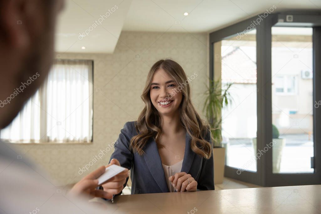 Beautiful businesswoman takes room key card and doing check-in at the hotel reception