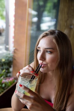 Güzel genç bayan kokteyl içiyor.