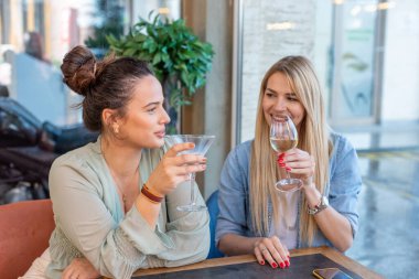 Restoranda şarap içen mutlu kız arkadaşlar.