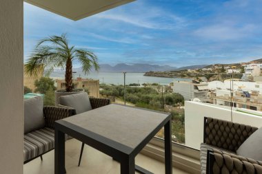 Otel tatil köyü terasları, koltuklar ve masa.