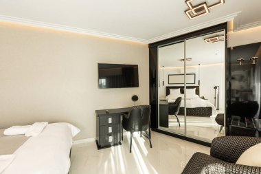 Lüks bir çift kişilik otel odasının içinde siyah beyaz mobilyalar var.