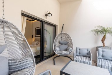 Otel tatil köyü terasları koltuk, masa ve sallanan yumurta koltukları.