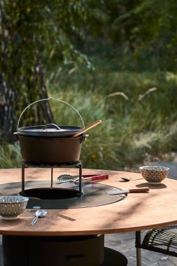 Tencere dibin kara seninki benden kara, seninki benden kara. Yuvarlak masa pişirme yüzeyi. Arka bahçede sıcak barbekü