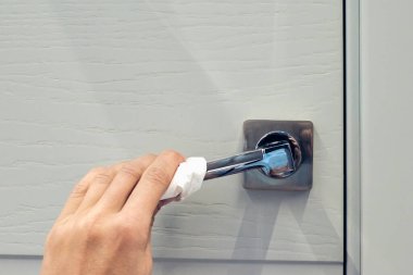 Coronavirus COVID-19 'un yayılmasını önleyecek eylemler, kapı kolunun dezenfekte edilmesi. Eldivenler, kapı kolunu dezenfektanla siler..