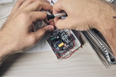 Elektronik cihazların tamiri, kalay lehimleme parçaları. Tornavida tutan adamın elleri. Bilgisayar devre kartı.